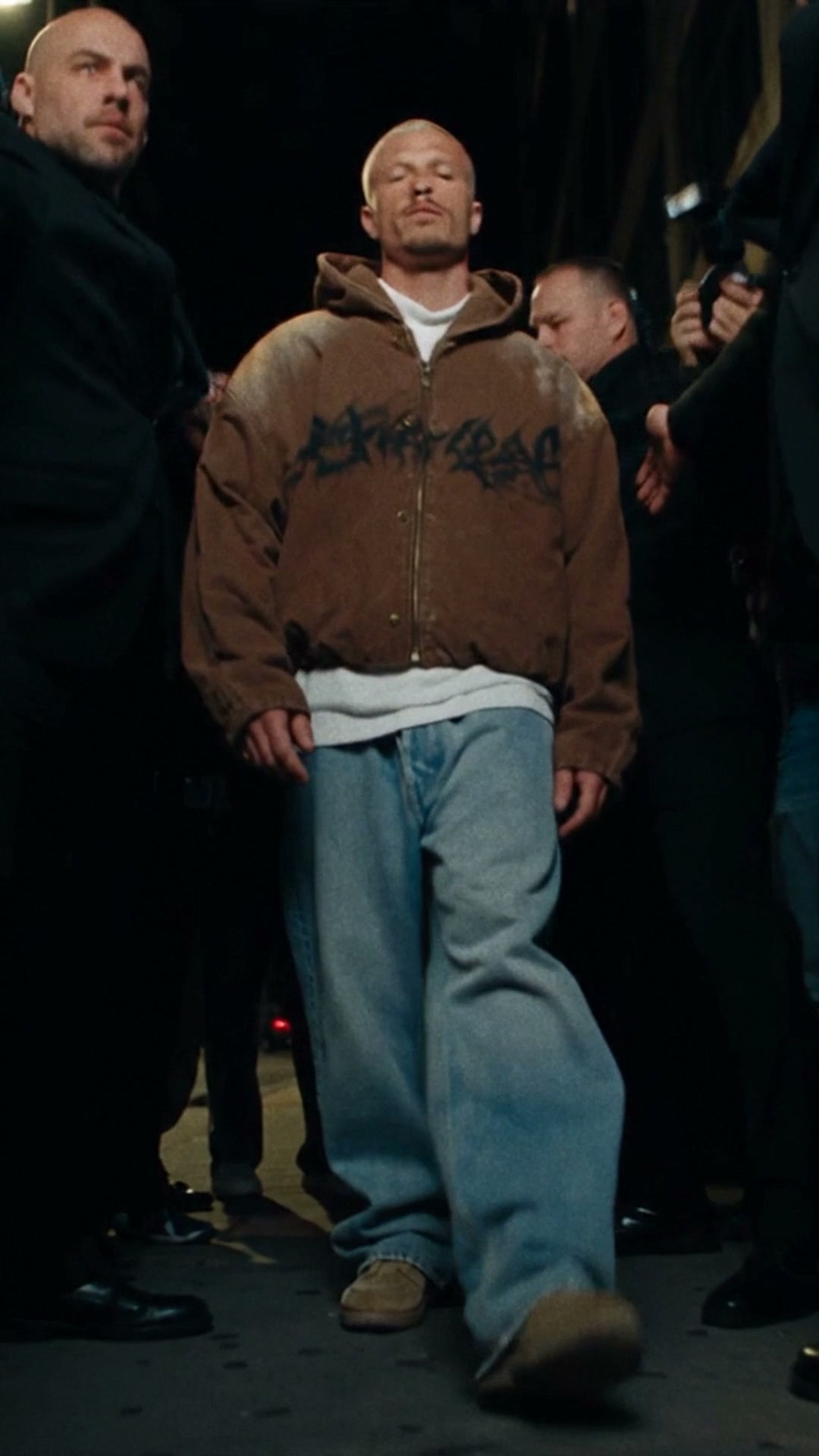 Artist walking between his entourage outside the venue